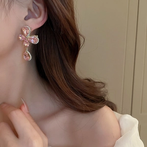 Gros plan de boucles d'oreilles pendantes en cristal rose et fleurs dorées sur un modèle