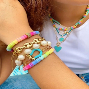 Detail view of layered bohemian bracelets with colorful heishi beads and gold charms