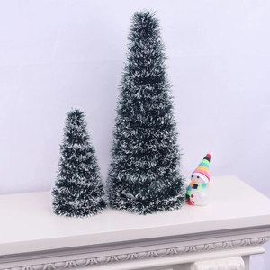 Close-up of dual green snow-tipped Christmas trees with snowman decor on a mantel