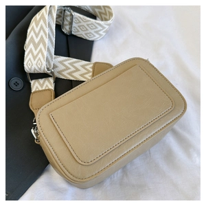Detail of beige PU leather crossbody bag with geometric woven wide shoulder strap