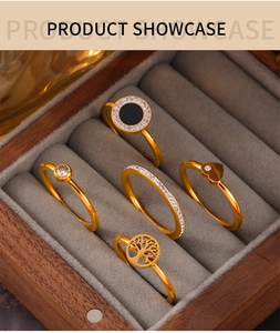 Detail of five gold-plated rings with Tree of Life, heart, and crystal designs in a display case