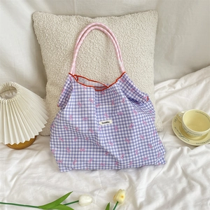Detail of purple plaid tote bag with pink bow pattern and woven ribbon handles