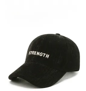 Detail of white STRENGTH embroidery on textured black corduroy baseball cap