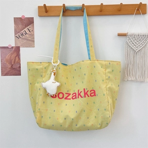 Detail of yellow checkered canvas tote with blue lining and plush goose charm detail