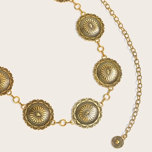Detailed macro view of vintage gold concho waist chain belt with embossed sunburst patterns