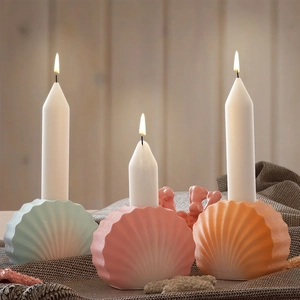 Bougeoirs en forme de coquillage aux tons pastels avec bougies sur fond de bois
