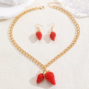 Detalle del collar de fresa dorado y pendientes a juego sobre una superficie blanca