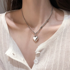 Detail of silver heart pendant necklace on model with bead and twisted chain style