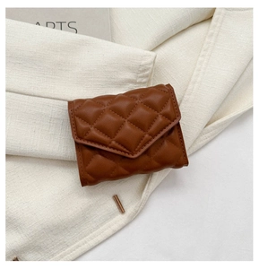 Detail of brown quilted leather mini card holder and coin purse on linen fabric