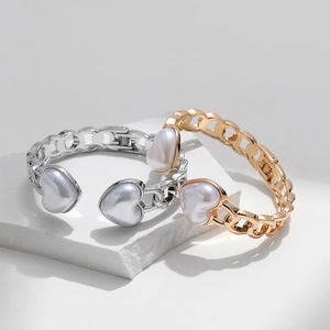 Elegant gold and silver link bracelets featuring three heart-shaped pearls on white stone