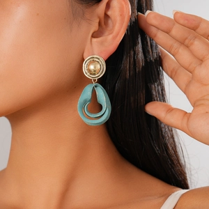 Detail von Retro-Ohrhängern mit Goldsteckern und blau lackierten Anhängern am Model