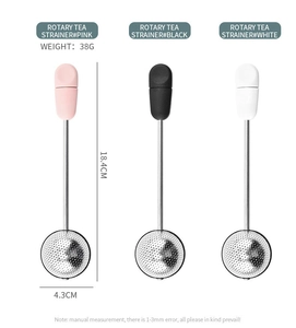 Close-up of three rotating mesh tea strainers in pink, black, and white colors