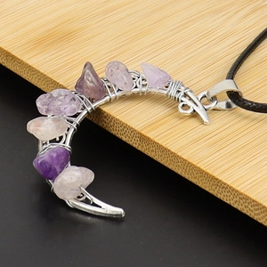 Detail of silver wire wrapped crescent moon pendant with purple and pink crystal stones