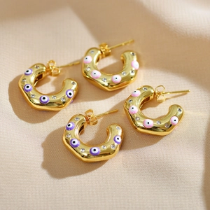 Detail of C-shaped gold earrings with colorful devil's eye charms and micro-inlaid zircon