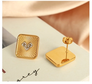 Detail of square gold earrings with heart shaped zircons showing front and back views