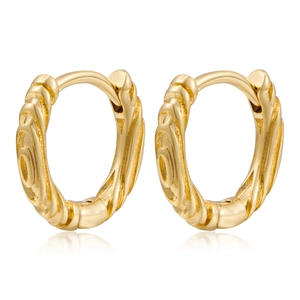 Macro detail of gold twisted huggie earrings showing polished metal texture and hinge