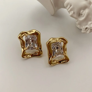 Detail of vintage gold zircon earrings with irregular lava metal frame and crystal