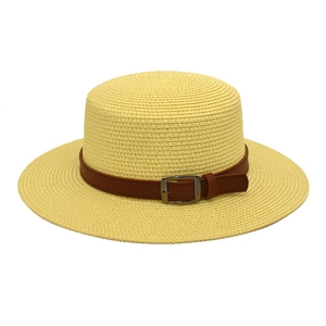 Detalle de un sombrero de paja trenzado con cinta de cuero marrón y hebilla de metal plateado