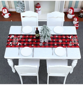 Detail van rood-zwarte geblokte tafelloper met Merry Christmas print en rendier decor