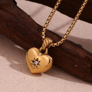 Macro shot of 18K gold plated heart pendant with zircon on dark wood texture
