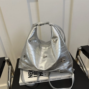 Borsa tote argento testurizzata con farfalle metalliche su sedia in pelle nera