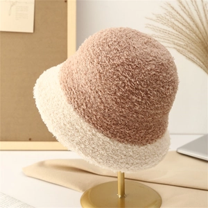 Gros plan du chapeau bob en peluche bicolore beige et marron sur un support