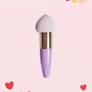 Detail of heart-shaped makeup sponge with purple handle and dense soft synthetic bristles
