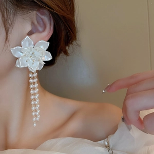 Dettaglio di orecchini a fiore 3D bianchi con lunghe nappe di perle su modella
