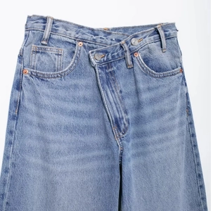 Jean femme bleu clair à jambes larges avec un design tendance à taille croisée asymétrique