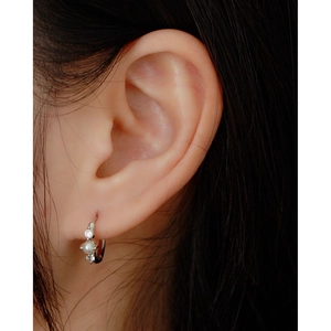 Close-up of 925 sterling silver pearl earrings with zircons worn by a model