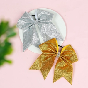 Sparkly gold and silver glitter bow hair ties with rhinestones on a white plate
