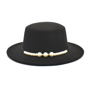 Detalle de un sombrero plano negro vintage con una elegante banda de perlas decorativas.