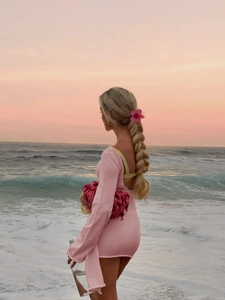 Detail of pink long-sleeved backless dress for beach resort with sunset backdrop