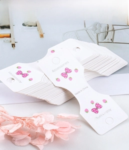 Dettagli di cartellini per accessori in cartoncino bianco con motivi a fragola e fori