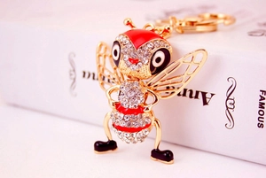Macro shot of bee keychain with red enamel and rhinestones on a golden metal base