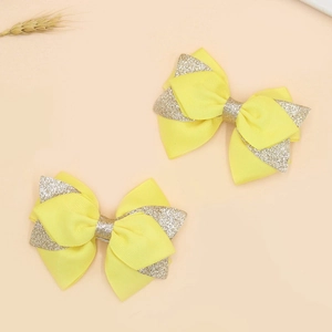 Close-up of yellow grosgrain ribbon hair bows with gold glitter sequins for children