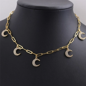 Gros plan du collier trombone doré avec cinq pendentifs lune sertis de zircons brillants