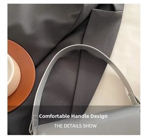 Detail showing the thin leather shoulder strap and fine stitching on the grey handbag