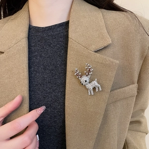 Detail of a crystal-encrusted reindeer brooch pinned on a beige blazer lapel