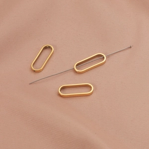 Three 18K gold-plated oval pendant connectors for DIY jewelry making on pink fabric