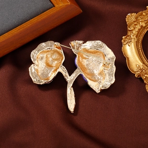 Elegant gold peony flower brooch with detailed back clasp on dark satin background