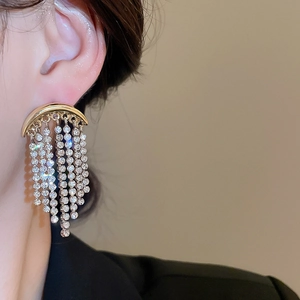 Gros plan de boucles d'oreilles lune dorées avec de longues franges en cristal brillant