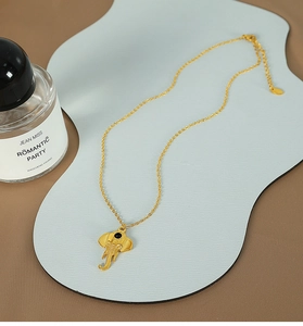 Detailed view of golden elephant pendant necklace with textured ears and black bead eye