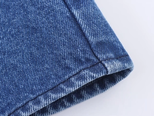 Detailaufnahme von blauem Denim-Stoff mit Doppelnähten und Köperbindung-Struktur