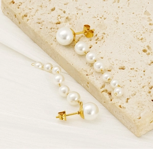 Macro view of long 18K gold-plated tassel earrings with gradient white pearls