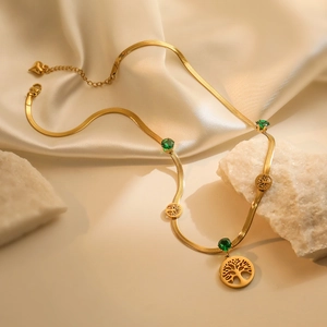 Gold tree of life pendant necklace with green stones on elegant silk backdrop