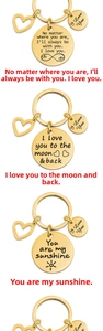 Detail of gold-plated stainless steel keychains with heart charm and engraved quotes
