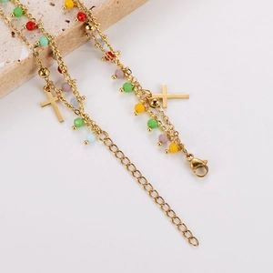 Détail de perles colorées et breloques croix dorées sur un bracelet en acier inoxydable