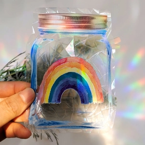 Rainbow prism suncatcher sticker in jar shape creating colorful light on a white wall