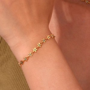 Detail of 18K gold plated flower bracelet with blue bead accents worn on wrist